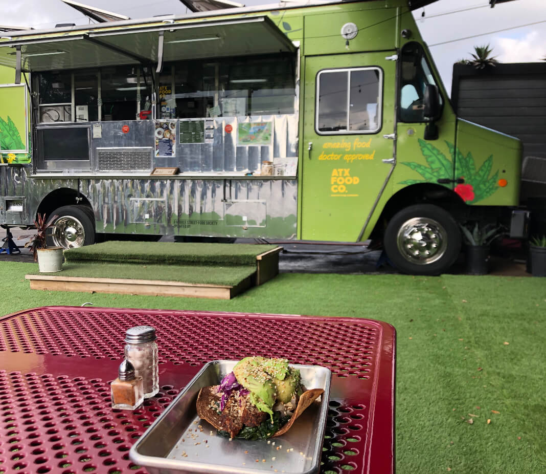 ATXFOODCO truck with a tray of food in front on a grassy area