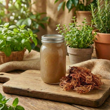 Mason jar with liquid on a wooden cutting board surrounded by potted plants